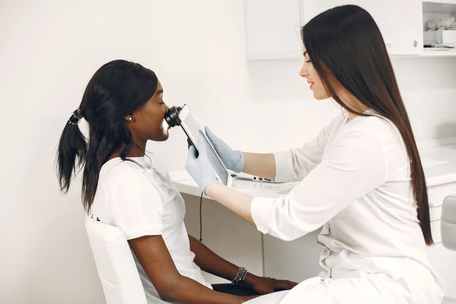 Clinician using a skin imaging device during a facial examination.