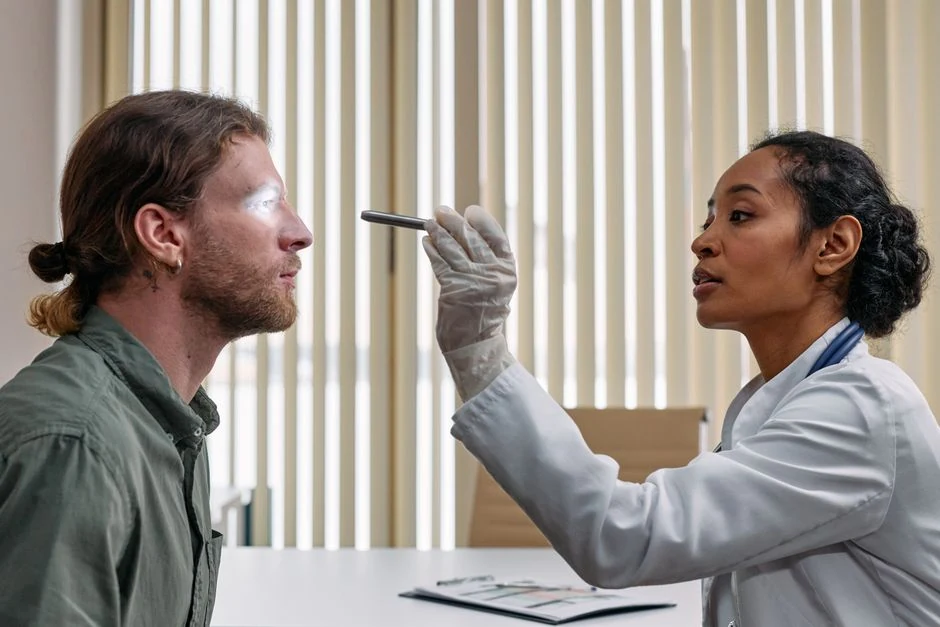 Clinician examining a patient's eye and upper eyelid during an in-office evaluation